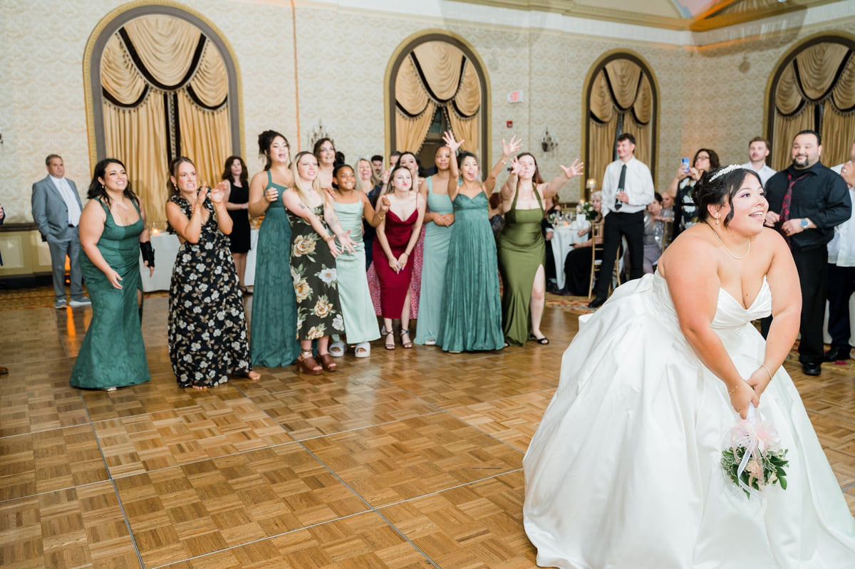 A big group of wedding guests dancing together under warm light